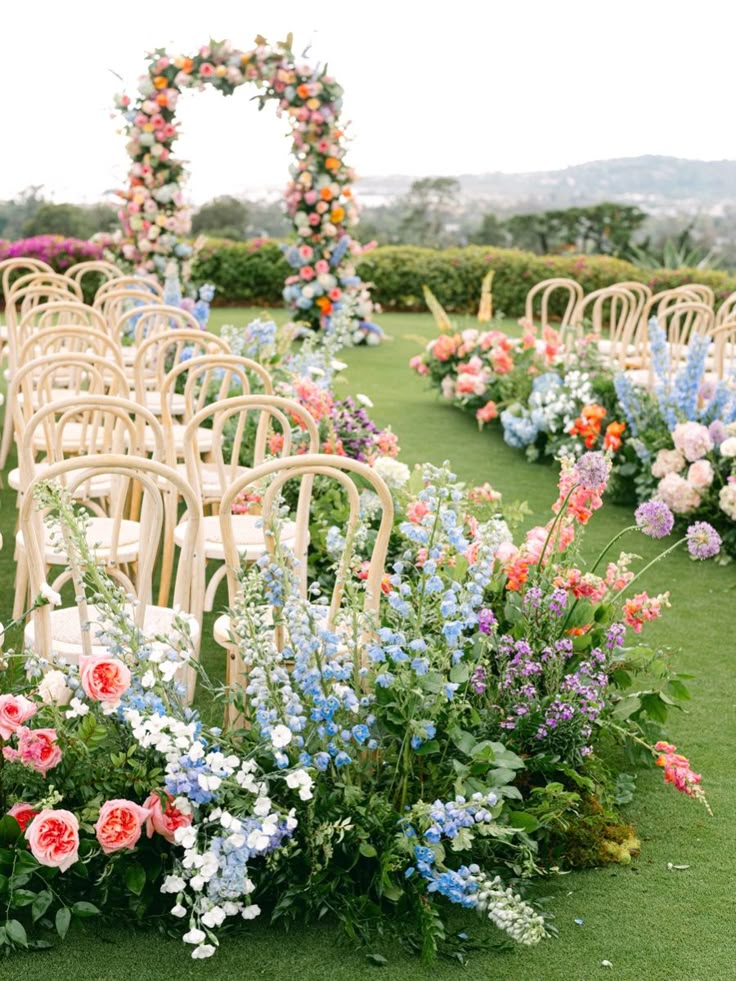 Decorative floral arch and pathway at an outdoor event with chairs.